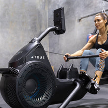 Load image into Gallery viewer, Woman training on the TRUE Rō rowing machine with MultiGrip handlebar